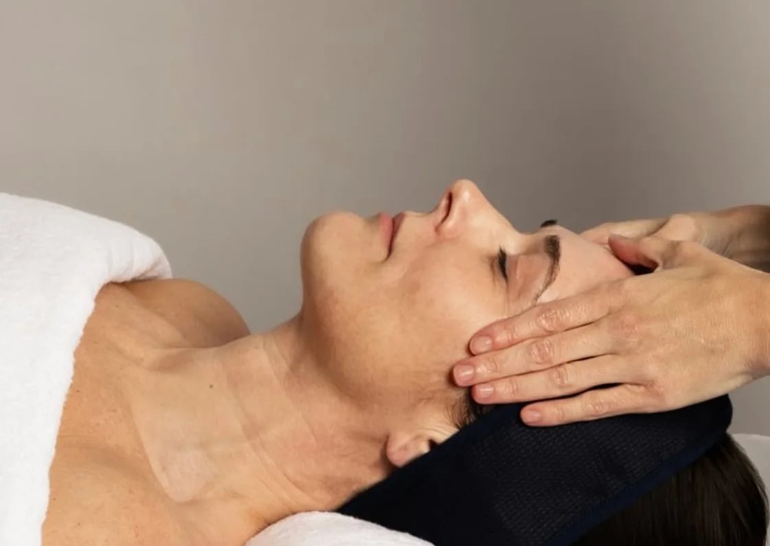 Client mid-treatment, hands cradling the face during The Hyperpigmentation Facial.